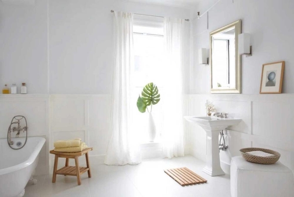 Bright white bathroom and dressing area location featuring a classic pedestal sink, natural light, and wooden accents in NYC, NY 10011, Love Locations.