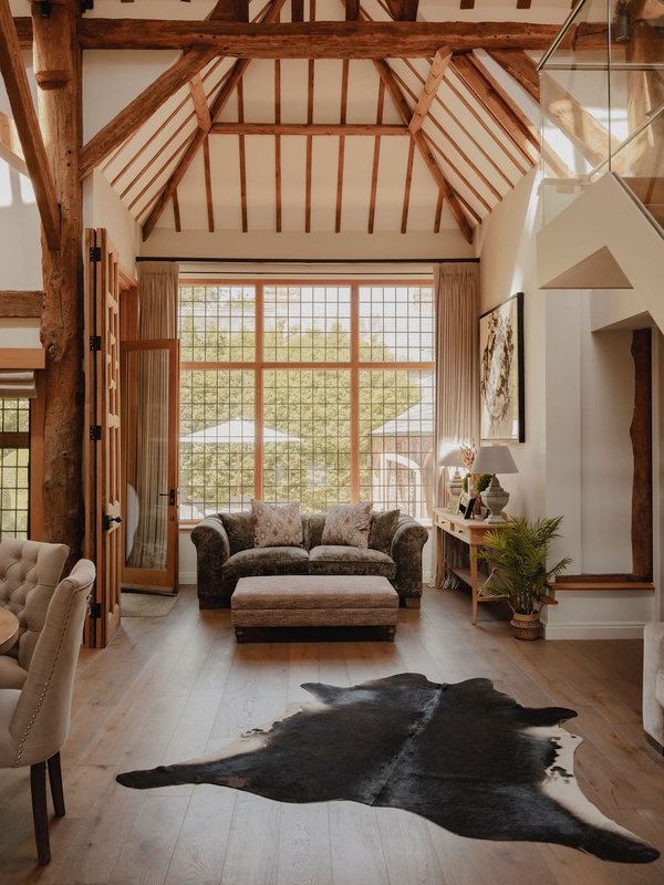 Grand cathedral-style barn interior with tall glass window doors, plush seating, and exposed timber rafters, Love Locations.