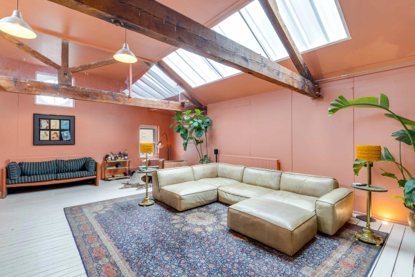 Boho-chic loft lounge location with a large leather corner sofa and ornate rug for lifestyle shoots, Love Locations.