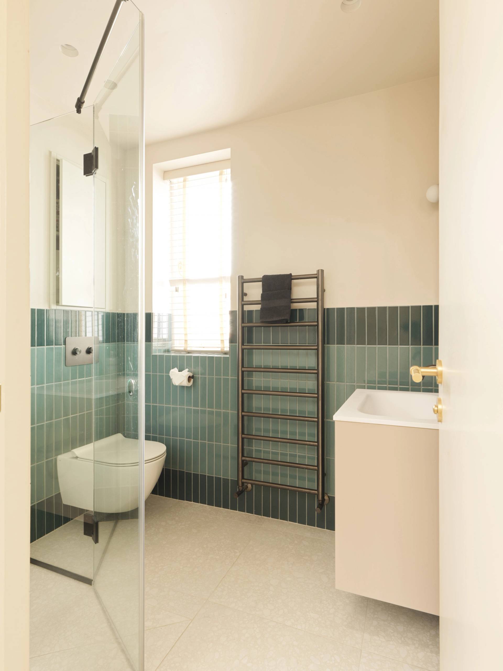 Contemporary bathroom shoot location with green stacked wall tiles, glass walk-in shower, and white vanity unit from Love Locations.