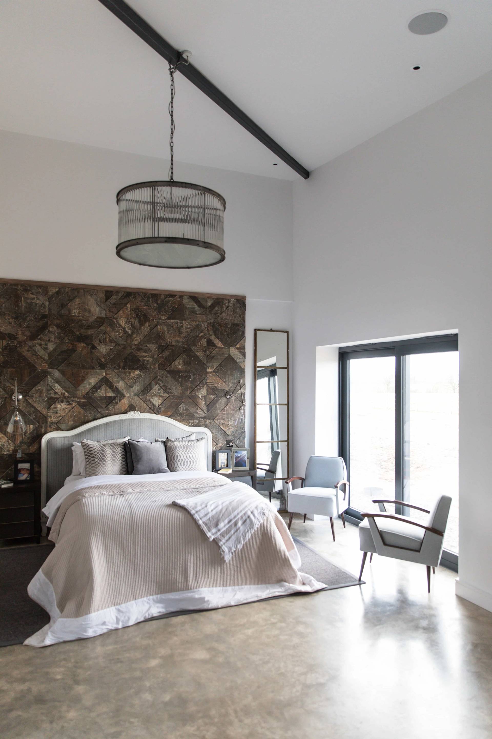 Spacious bedroom suite with patterned upholstered headboard wall, armchairs, and polished concrete floor, Love Locations CV23.