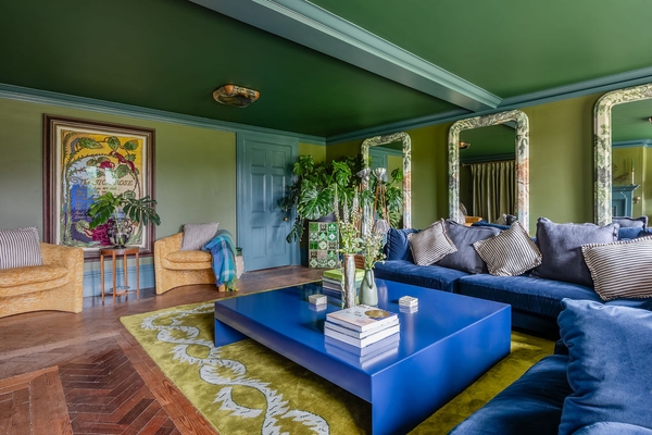 Sophisticated reception room with modern blue lacquered furniture arrangements on an ornate green rug, a premium production space by Love Locations.
