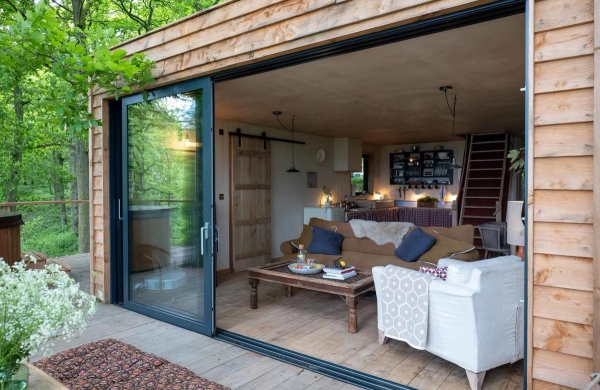 View looking in from a wide open glass patio door into a warmly lit, inviting rustic living room layout, perfect for winter lifestyle shoots, Love Locations.