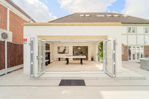 Exterior view of open bi-folding glass doors leading into a luxury mansion games room, Love Locations RM11.