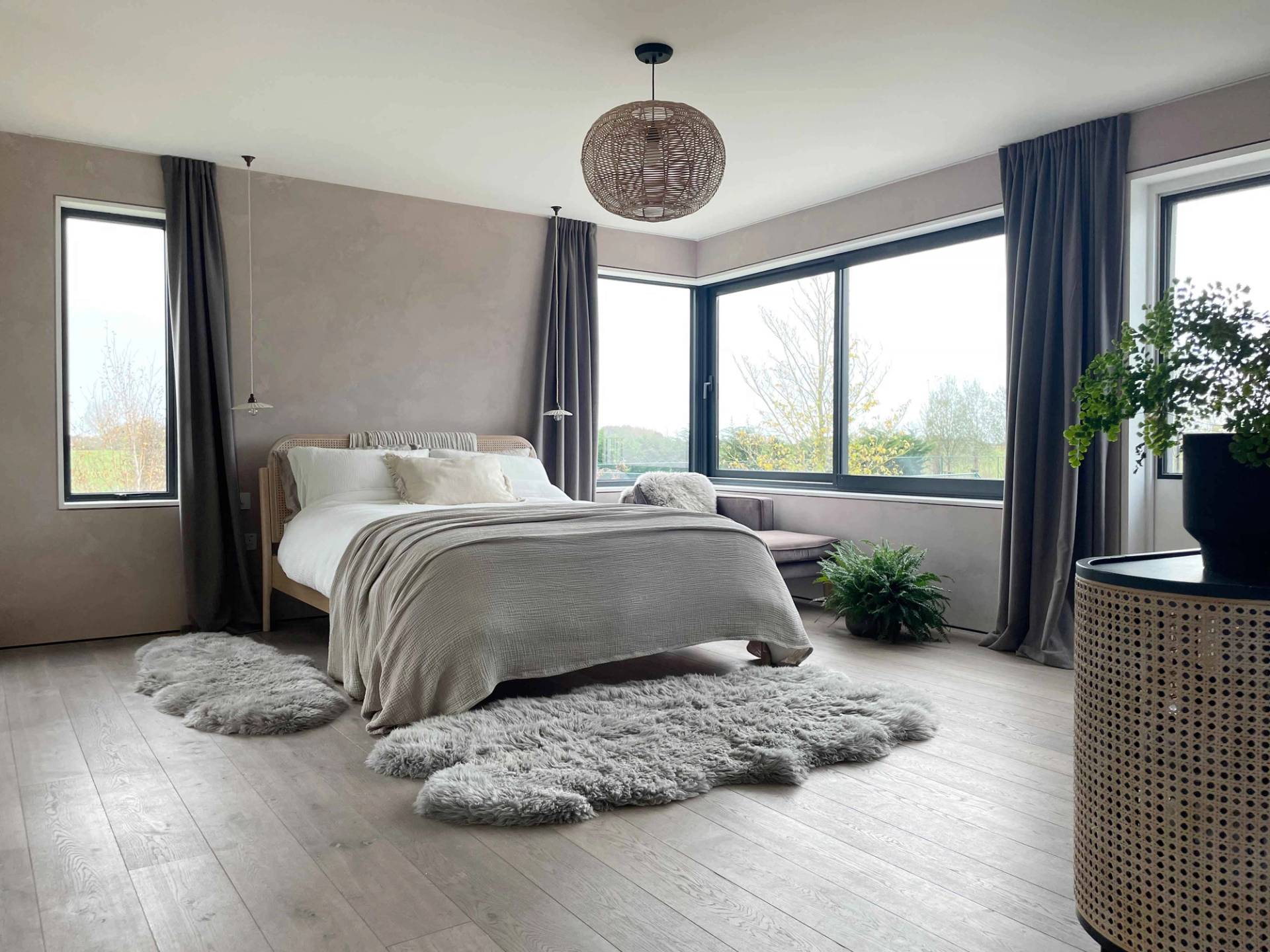Minimalist master bedroom suite featuring corner picture windows, neutral linen bedding, and sheepskin rugs, ideal for mattress and sleepwear brand campaigns, Love Locations.