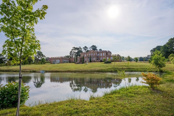 Picturesque landscape view of the Greentrees manor house reflecting across its private estate lake, a scenic film location by Love Locations.