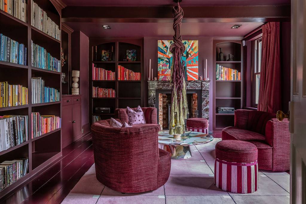 Cozy library film location in Liss Hampshire GU33 from Love Locations, featuring deep purple walls, custom built-in bookshelves, and comfortable seating.