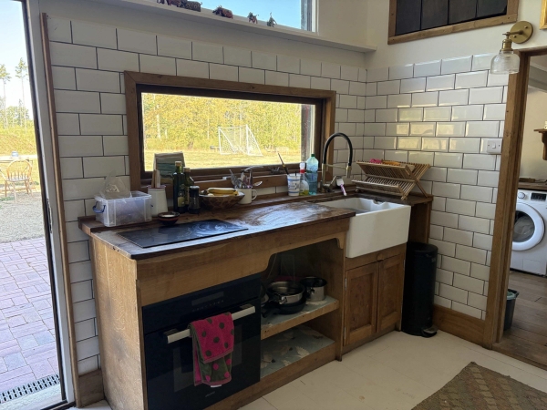 Rustic farm kitchen workspace featuring a ceramic butler sink, timber cabinetry, and subway wall tiles, Love Locations BN8.