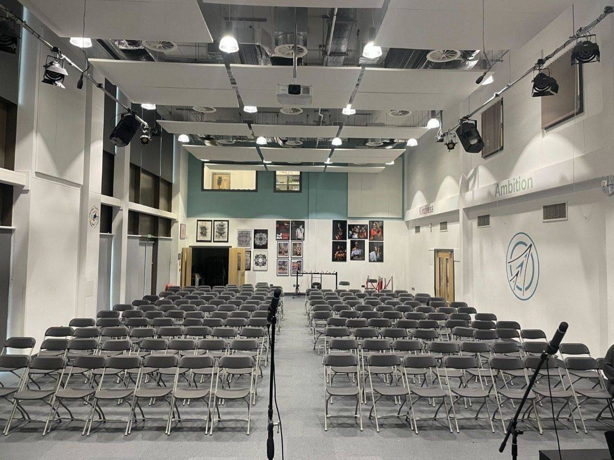 Love Locations school assembly hall Reading RG30: Deep presentation space filled with organized seating under industrial studio lighting, perfect for institutional events and theatre scenes.