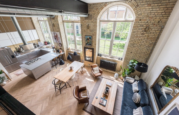 High-angle dramatic look at an industrial loft apartment location with double-height ceilings and parquet floors, Love Locations.