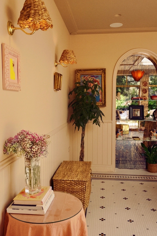 Cozy hallway vignette featuring a fresh pink floral arrangement and a tall houseplant against pale striped walls, Love Locations Hounslow.