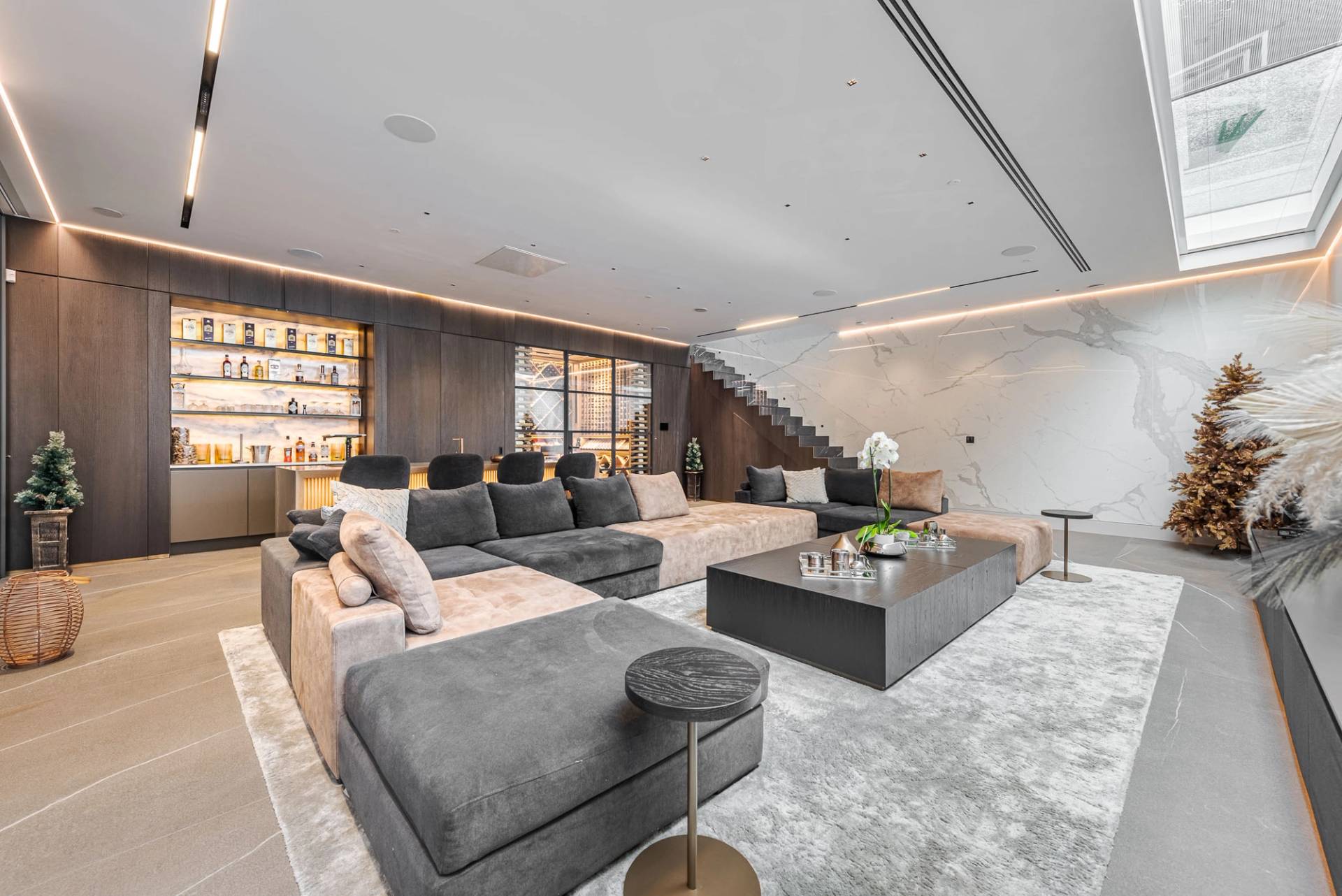 Subterranean entertainment lounge with plush grey sectional sofas, ambient strip lighting, and marble coffee tables, Love Locations SW11.