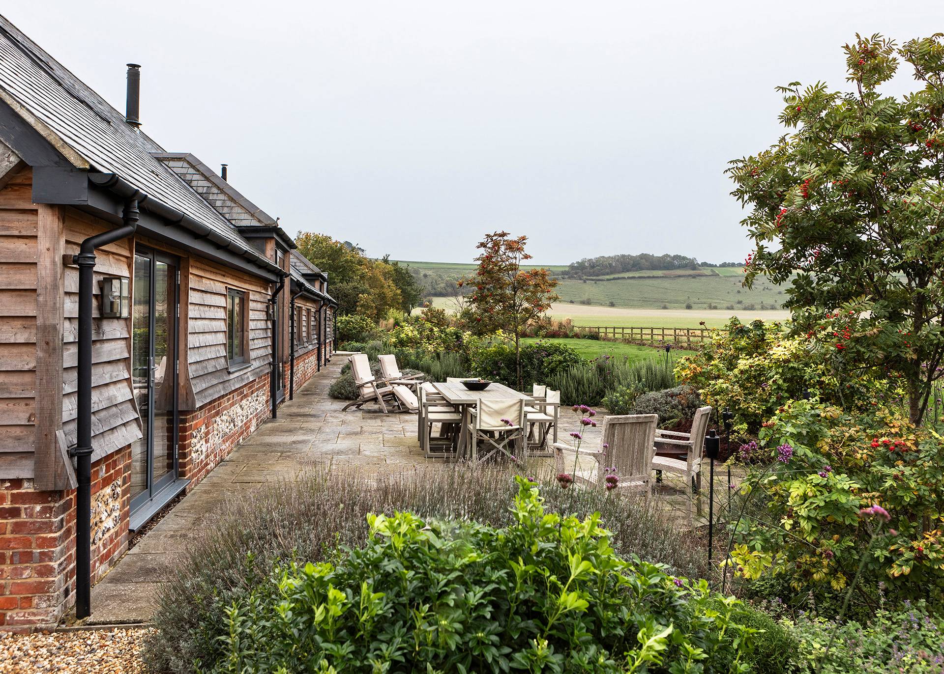 Wide garden terrace set with outdoor lounge furniture overlooking open Wiltshire fields, Love Locations SN8.
