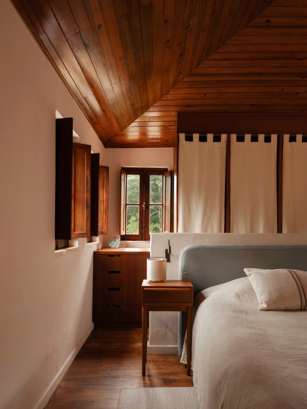 Master bedroom suite with sloped timber ceiling, white linen bedding, and wooden shutters, Love Locations 2705-064.