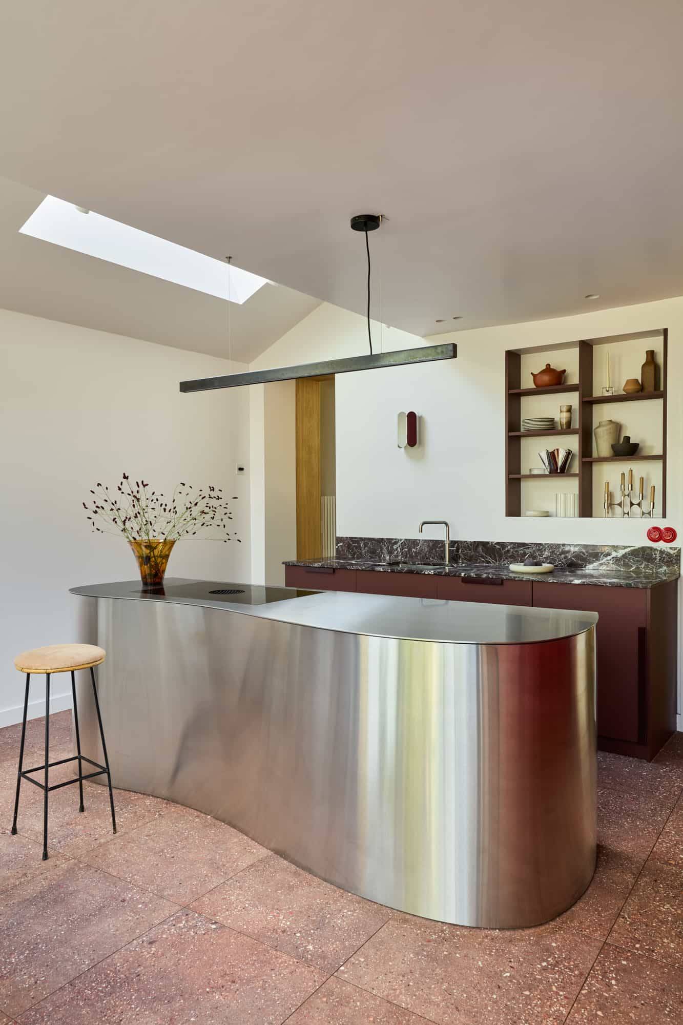 Love Locations luxury home location SE23: Minimalist kitchen layout highlighting a bespoke metallic island block and geometric skylights, perfect for commercial filming and editorial lookbooks.