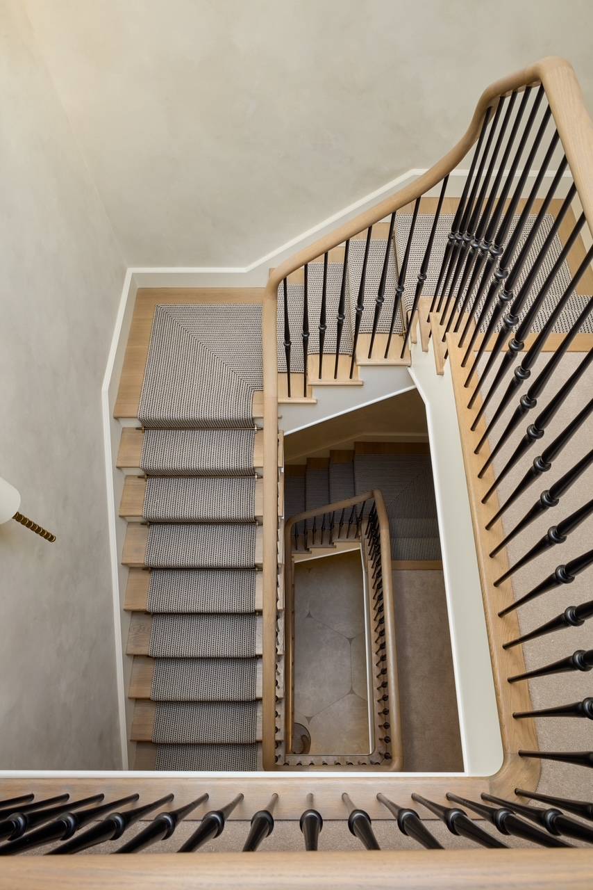Architectural perspective looking up a geometric multi-level stone stairwell with custom metal handrails, ideal for artistic architectural publications via Love Locations.