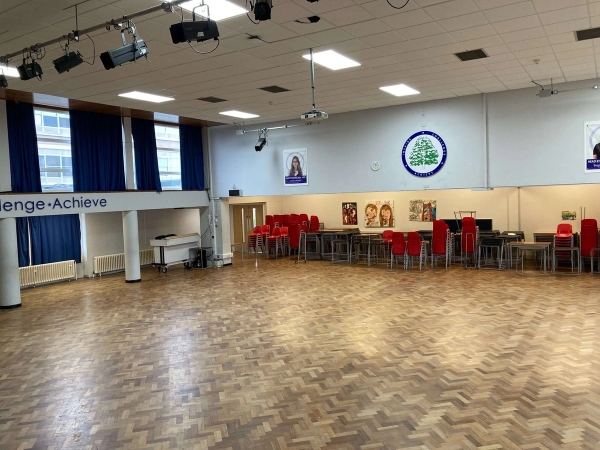 Love Locations institutional hall shoot space Chelmsford: Substantial indoor communal area with a timber floor, track lighting, and a school logo crest, tailored for television series and student lifestyle photography.