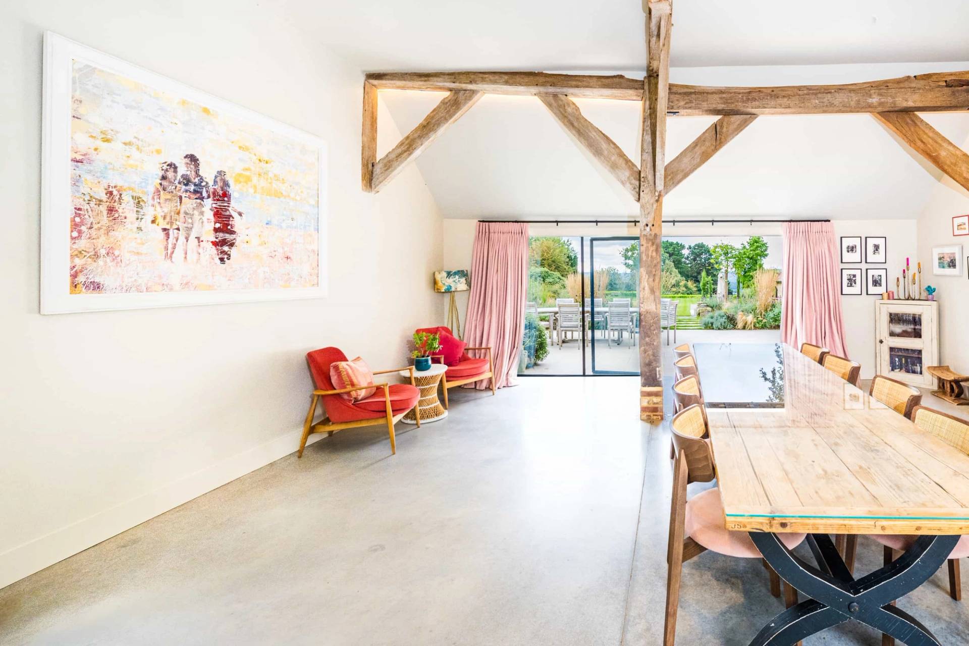 Vaulted barn reception space with exposed timber trusses, red armchair seating, and glass sliding patio doors, Love Locations GU28.