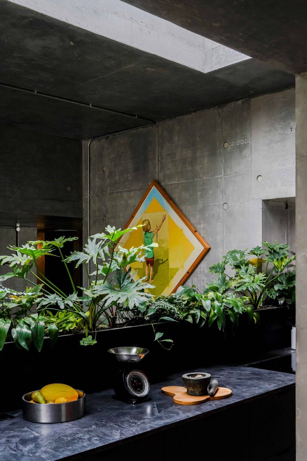 Brutalist concrete room detail with vibrant indoor tropical plants and yellow diamond wall art, Love Locations BN7.