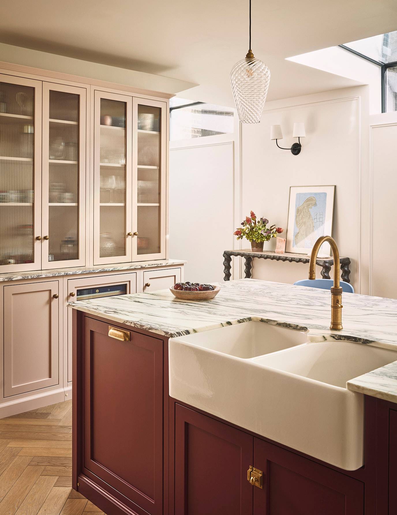 Deep red kitchen island featuring a double ceramic butler sink, brass mixer tap, and marble worktops, Love Locations SE21.