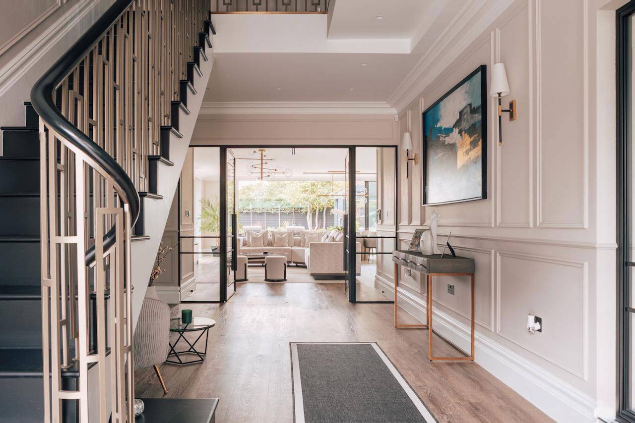 Grand entrance hall with dark wood floorboards, wall panelling, and a metal-balustrade staircase, perfect for welcoming film scenes, Love Locations.