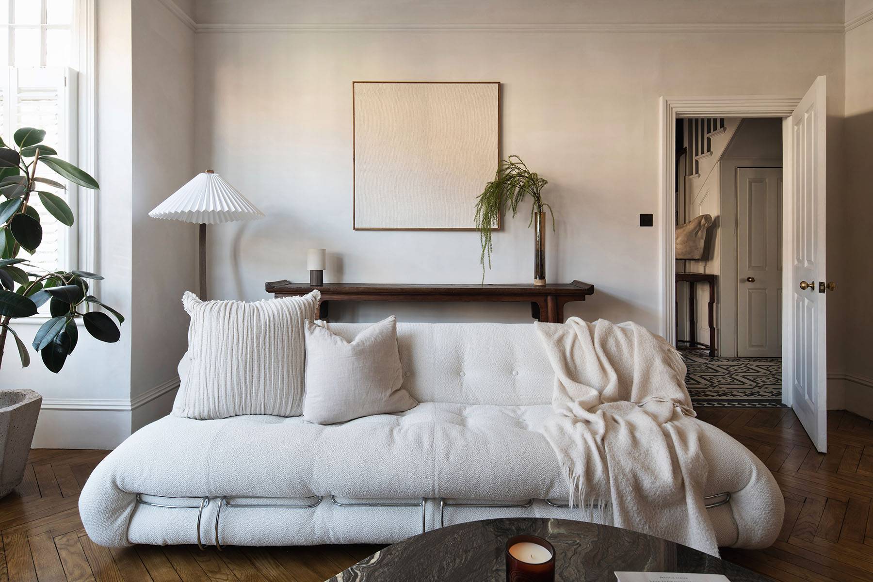Minimalist lounge corner with cream wabi-sabi plaster walls, dark wooden bench, and botanical vase, ideal for homeware lookbooks, Love Locations SW16.