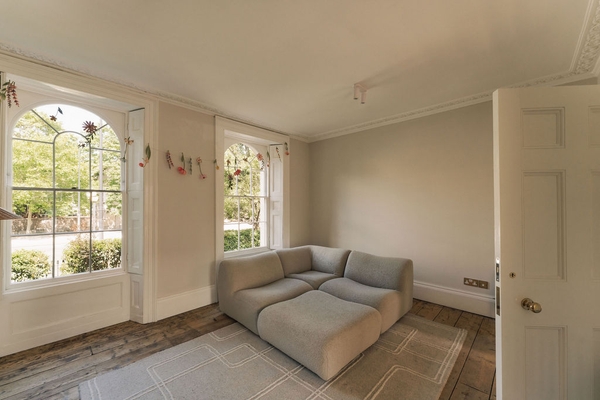 Minimalist lounge seating arrangement near tall Georgian-style sash windows, great for editorial furniture photography, Love Locations SW9.