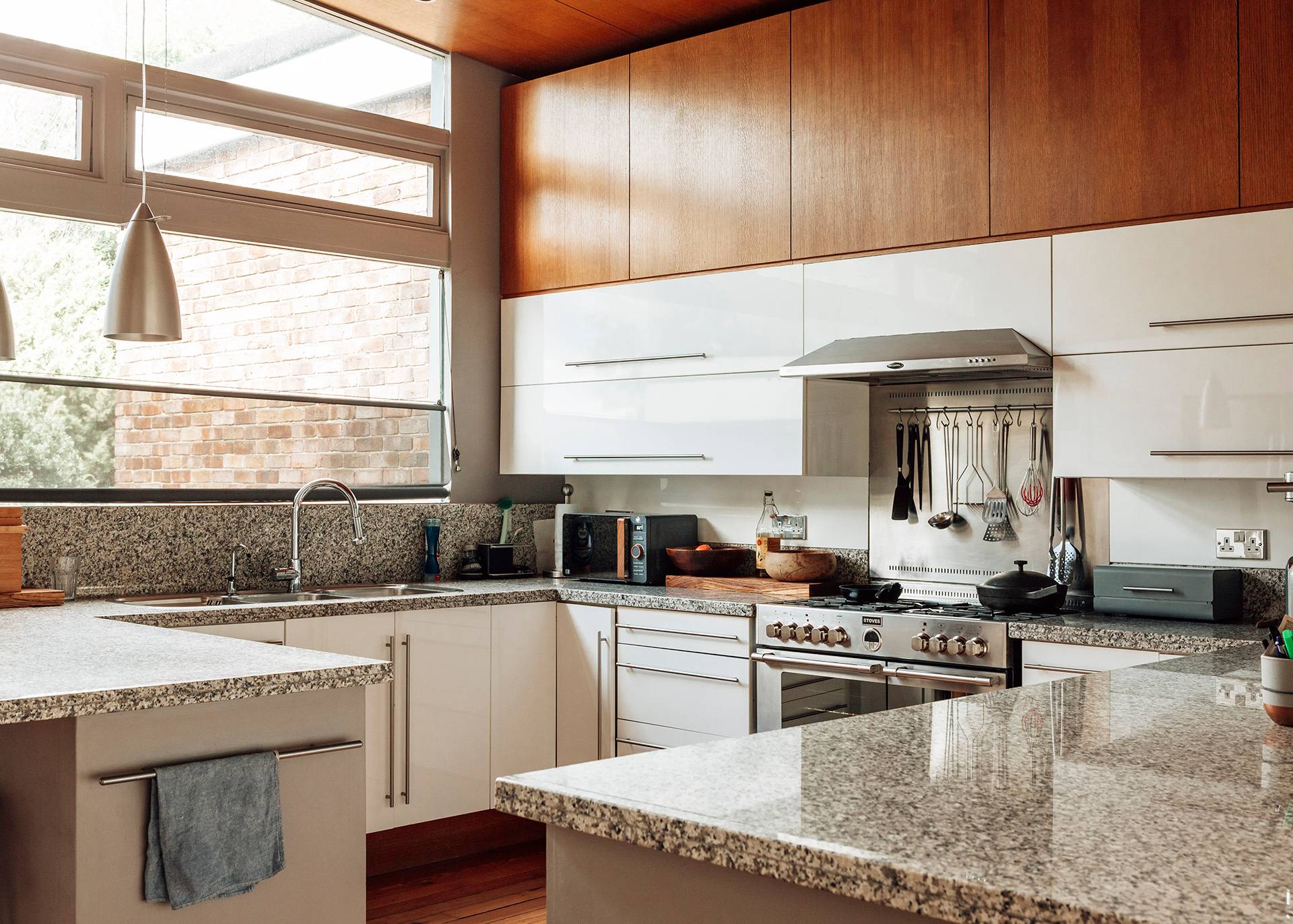 Mid-century modern kitchen featuring white cabinetry, wooden upper cupboards, and granite countertops, ideal for commercial cooking ads via Love Locations.