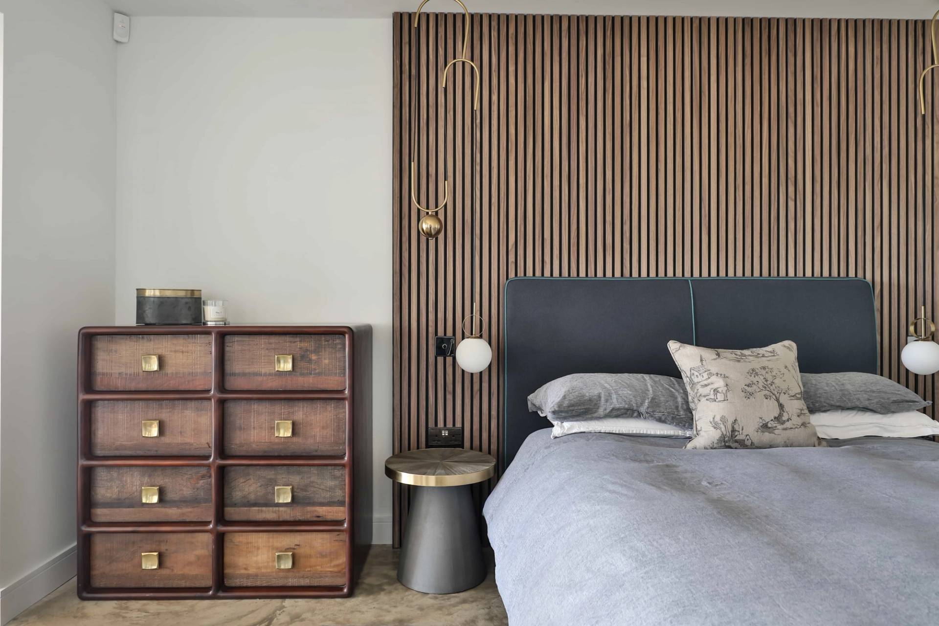 Bedroom detail view showing a dark wood chest of drawers beside a slatted timber headboard, Love Locations CV23.