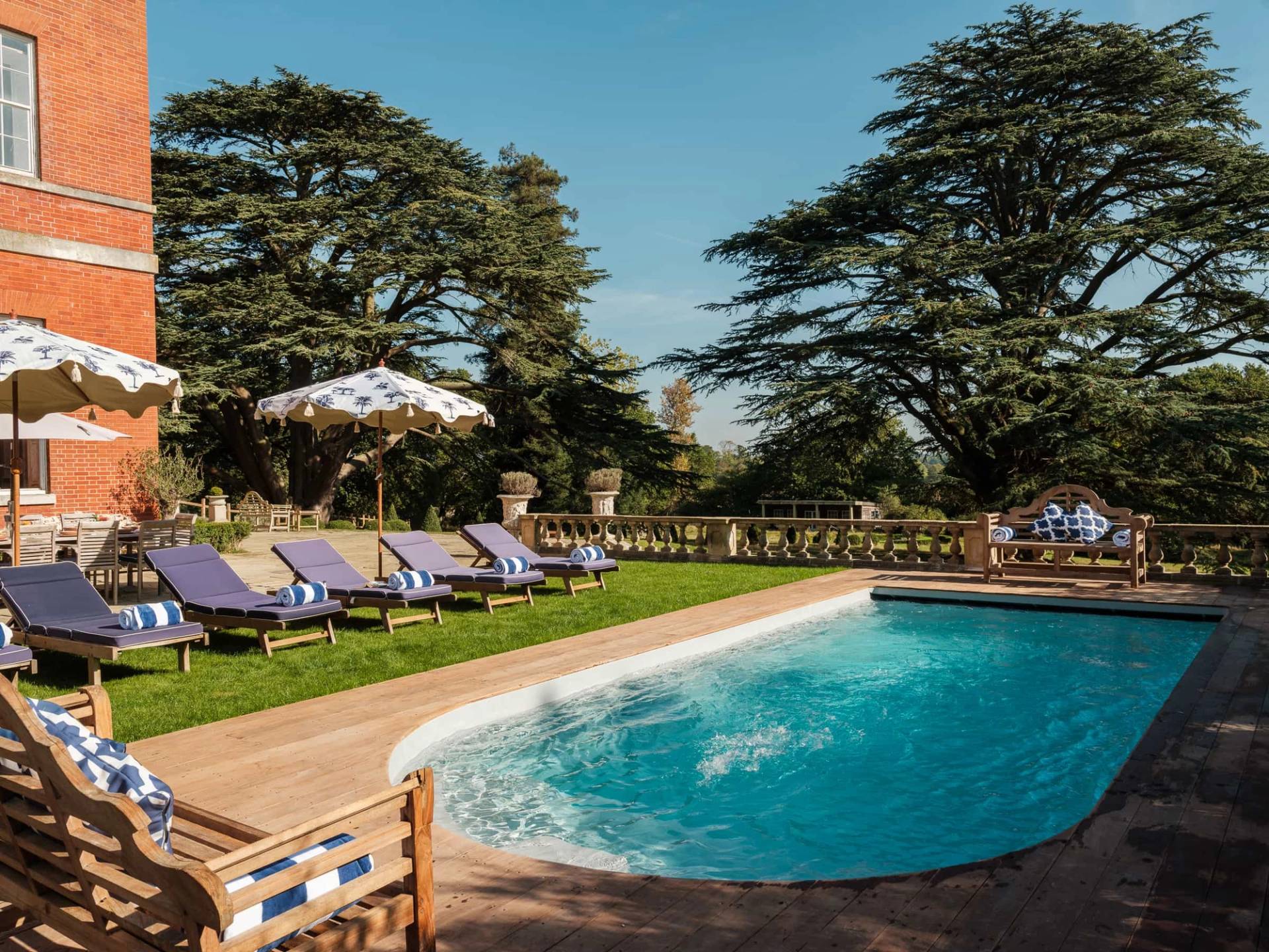 Outdoor swimming pool set against stone terrace walls and striped lounger cushions in Berkshire, Love Locations RG42.