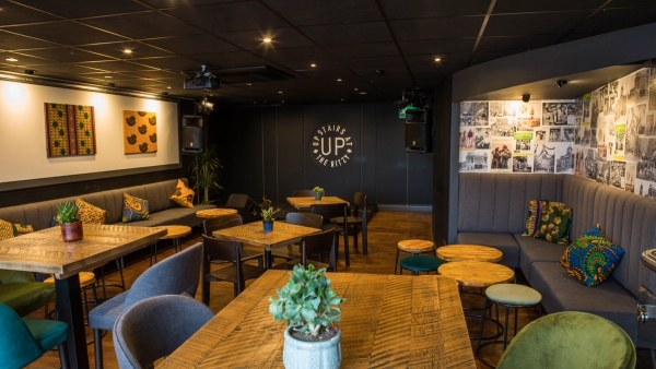 Bespoke bar lounge seating area with warm spotlighting, timber coffee tables, and dark acoustic ceiling tiles, suitable for intimate interview filming, Love Locations.