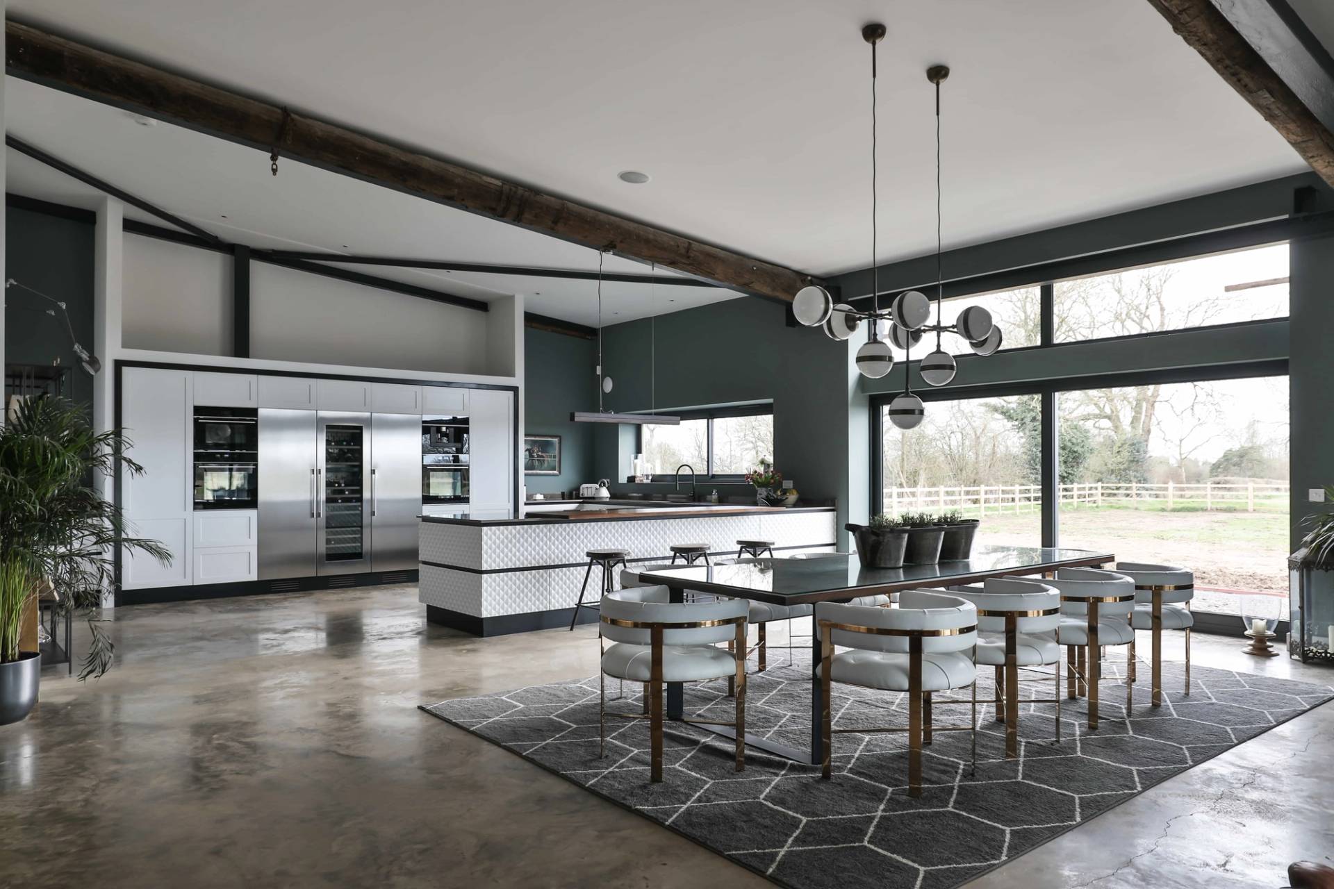 Modern converted barn shoot location in Bourton, CV23 featuring an expansive open-plan kitchen, dining area, polished concrete floors, and steel beams via Love Locations.