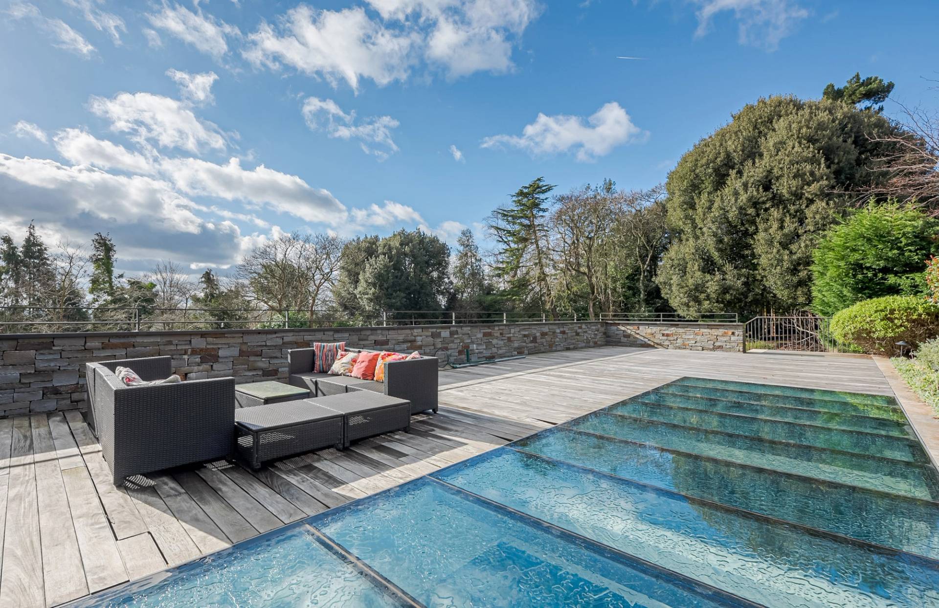Rooftop decking terrace view showcasing the walk-on glass swimming pool skylights and lawn gardens, Love Locations KT2.