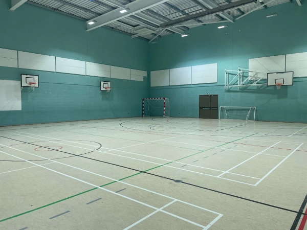 Love Locations indoor gymnasium film location Reading RG30: Expansive multi-sports court showing teal panelled walls and professional lighting trusses, optimized for athletic training videos and fitness brand shoots.