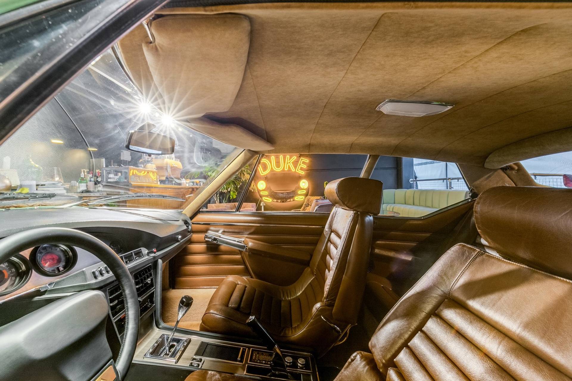 View from inside a vintage car looking out toward the DUKE neon sign in a Brentford location venue from Love Locations.