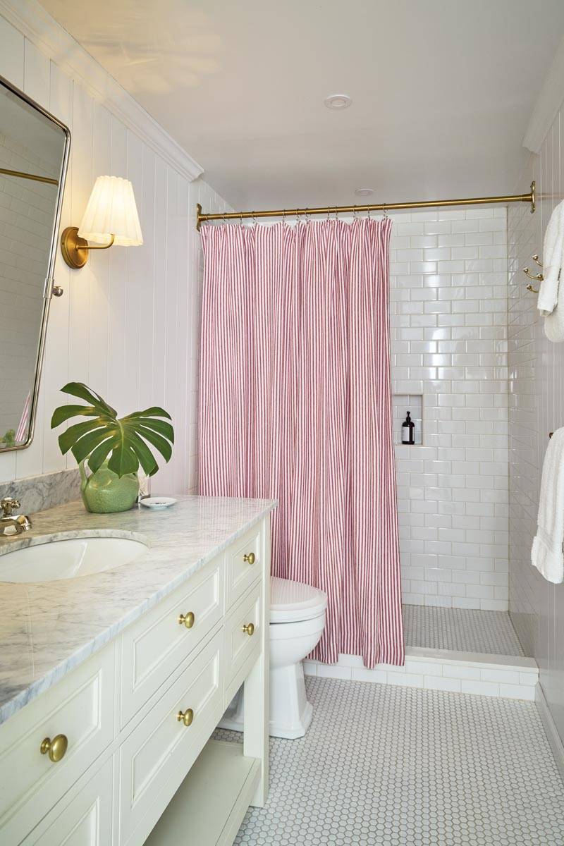 Modern white tile bathroom filming location featuring a pink ruffled shower curtain, white vanity unit, and gold bathroom fixtures in Manhattan NYC from Love Locations.