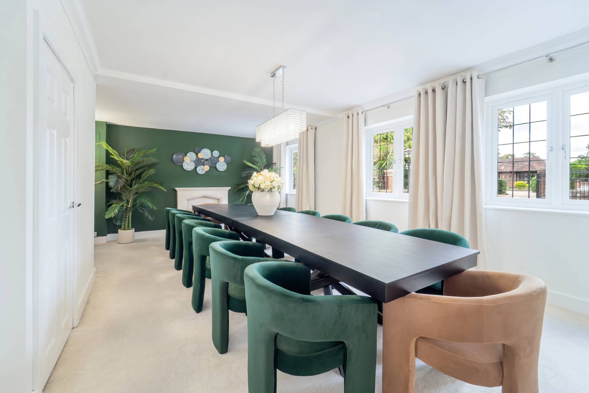 Formal dining room with long dark wooden dining table, forest green velvet chairs, and green feature wall, Love Locations RM11.