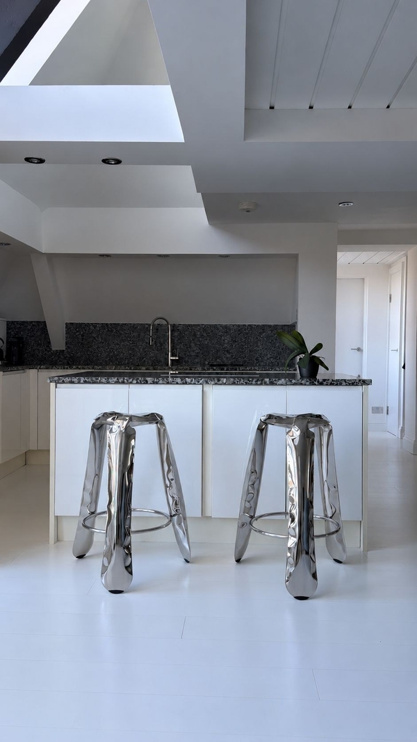 Sleek contemporary kitchen island setup for food photography in Brixton SW4 through Love Locations, featuring two industrial chrome bar stools, a white countertop, and dark wall tiles.