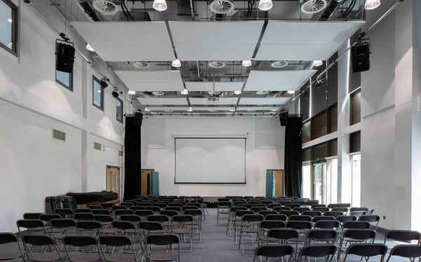 Love Locations auditorium film location RG30: Large lecture hall with rows of dark seating facing a blank presentation screen, optimized for corporate video, presentations, and drama scenes.