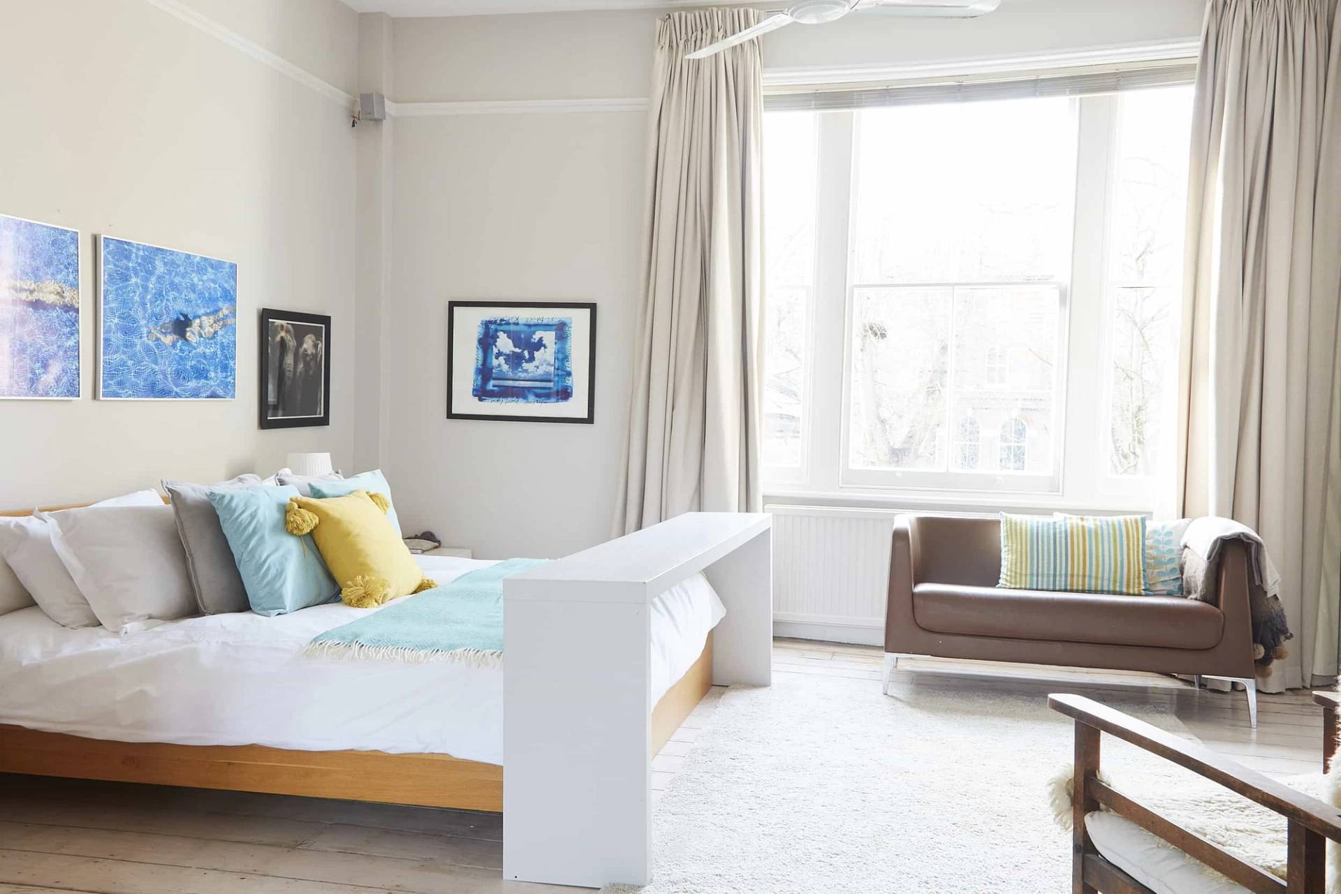 Master bedroom suite with a low timber bed frame, white painted floorboards, and view into an adjacent dressing area, Love Locations N5.