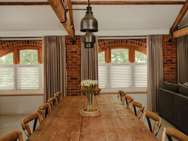 Detail of a large rustic wooden dining table with floral centerpieces and industrial pendant lights in a Oxfordshire home barn, ideal for luxury tableware lookbooks, Love Locations RG9.