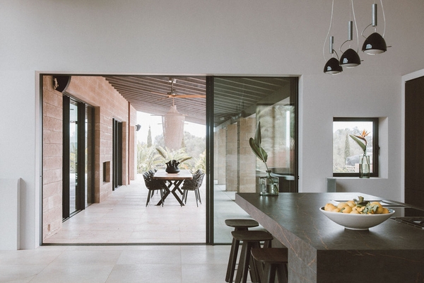 Glazed sliding doors opening from a modern kitchen onto a stone patio dining terrace, Love Locations 07630.