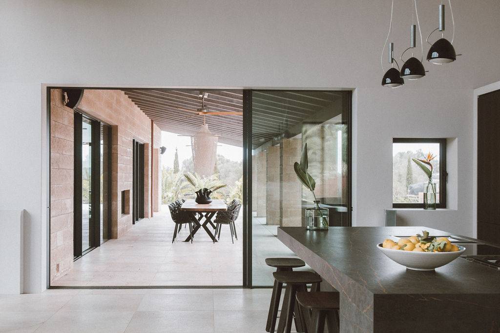 Glazed sliding doors opening from a modern kitchen onto a stone patio dining terrace, Love Locations 07630.