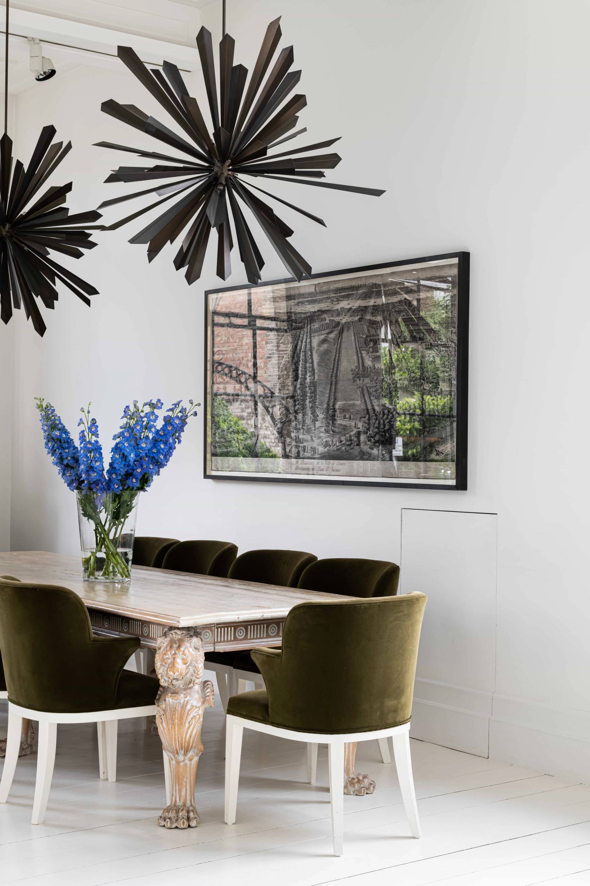 Dining area featuring a light wood dining table, moss green velvet chairs, and a spiky black modern chandelier, perfect for interior design features, Love Locations SW11.