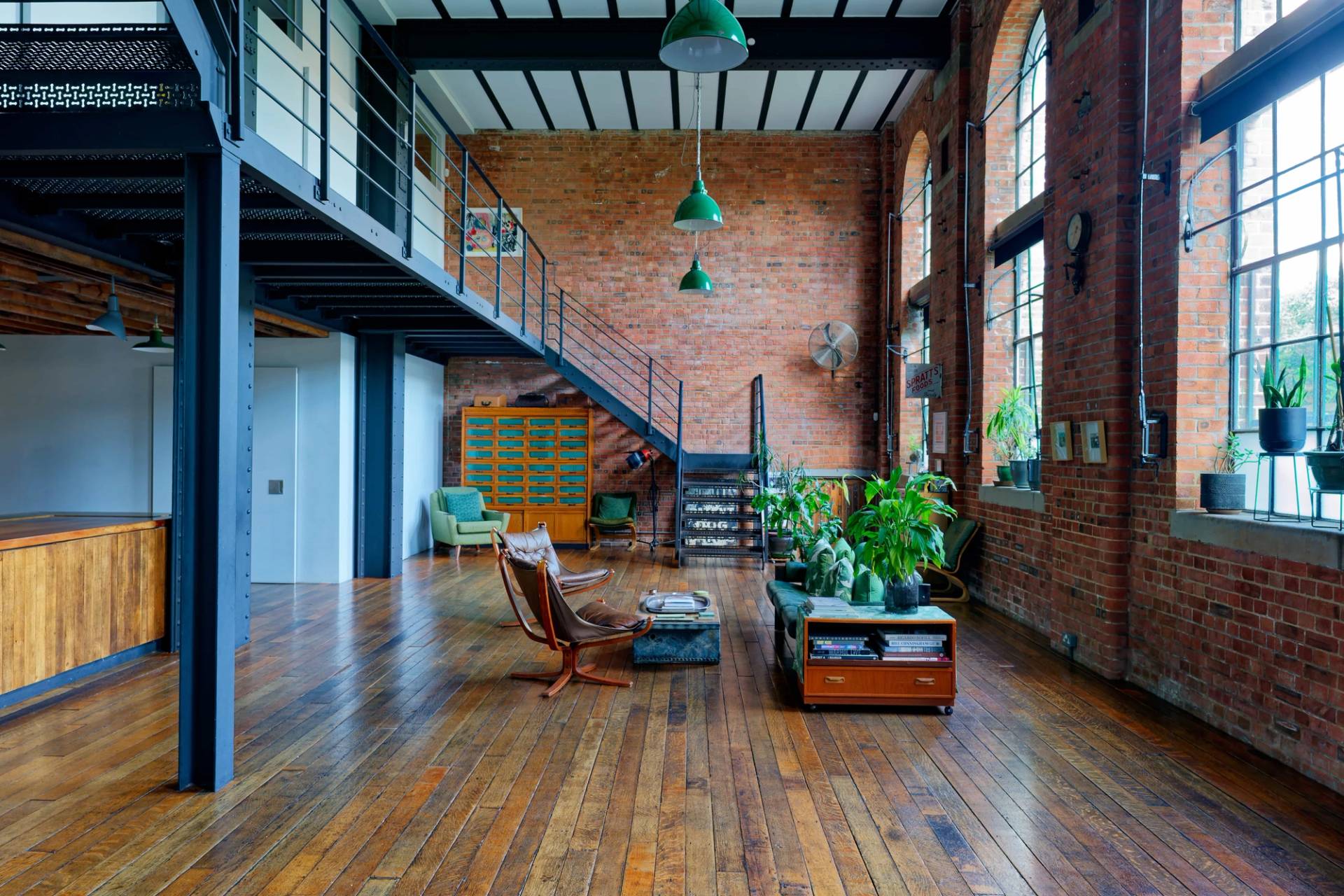 Double-height warehouse living space with steel staircase, vintage green filing cabinets, and potted floor plants, ideal for fashion editorials, Love Locations.
