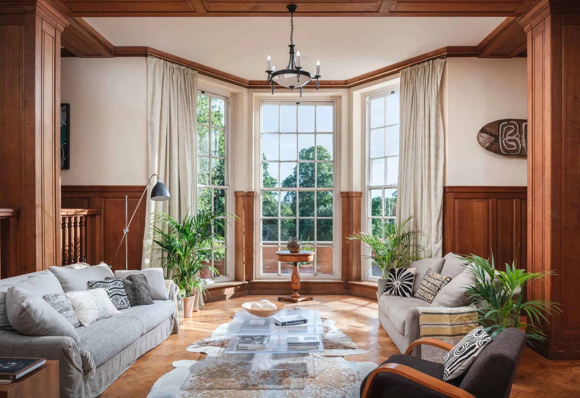 Light-filled living room film location in Totnes Devon TQ12 by Love Locations, featuring a deep bay window, wood wall panelling, and neutral soft furnishings.