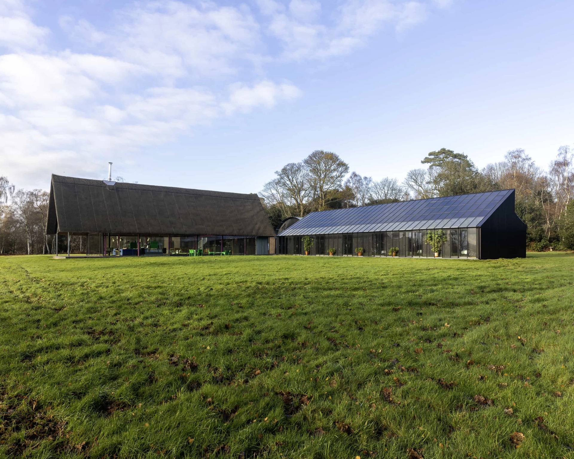 Wide landscape view showing modern thatched buildings and dark wooden outbuildings set in open Suffolk fields, Love Locations IP17.