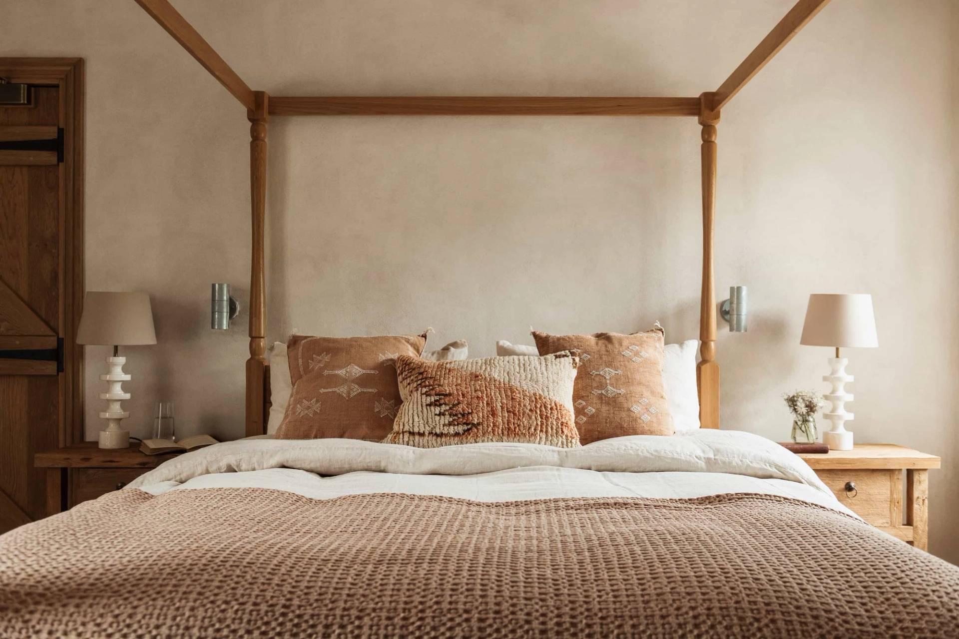 Rustic wooden four-poster bed location in Castleblayney County Monaghan Ireland from Love Locations, featuring earthy terracotta cushions and soft natural light.