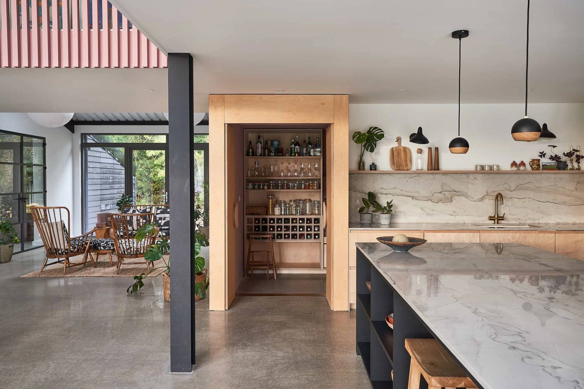 Industrial kitchen view looking through black steel supports toward built-in wooden pantry shelving, Love Locations IP30.