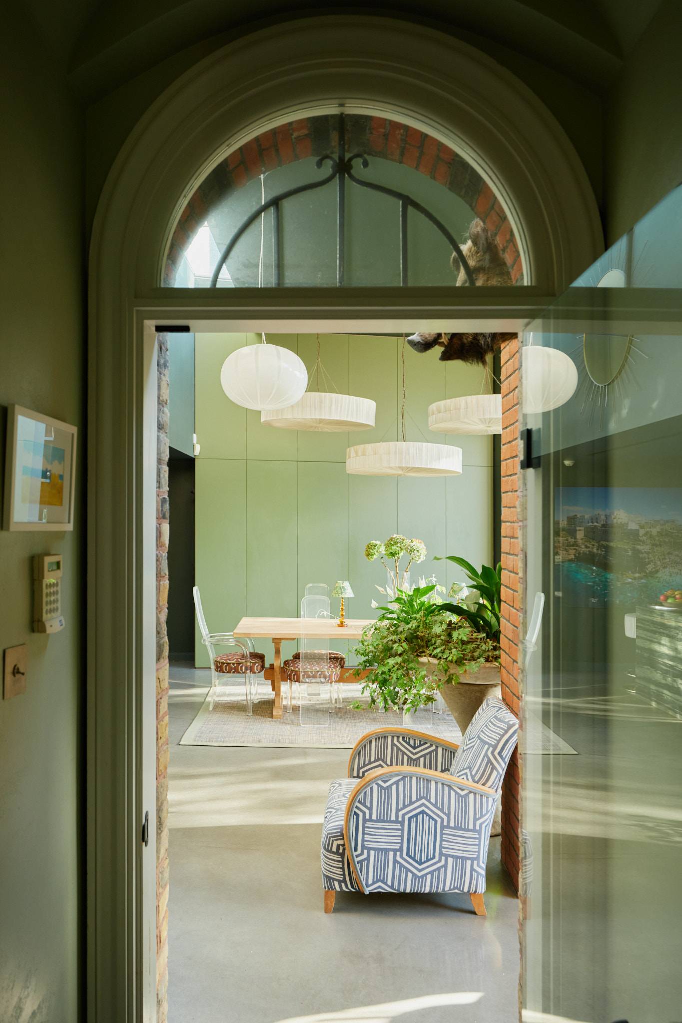 Glazed arched doorway looking into a double-height modern extension with paper globe pendant lights, Love Locations SW20.